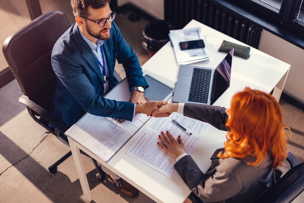 Happy bank manager shaking hands with a client after successful agreement in the office.