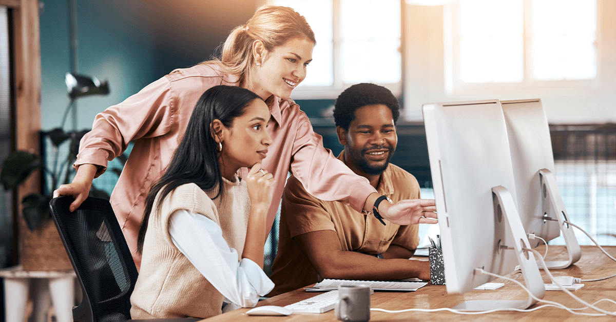 group of happy employees working together around a computer