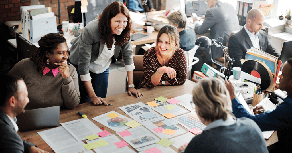 group of happy employees gathered around table