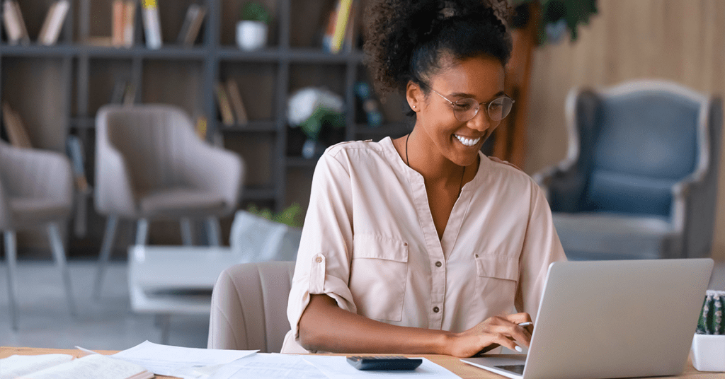 happy woman smiling at her laptop at home