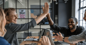 young happy employees high fiving around table